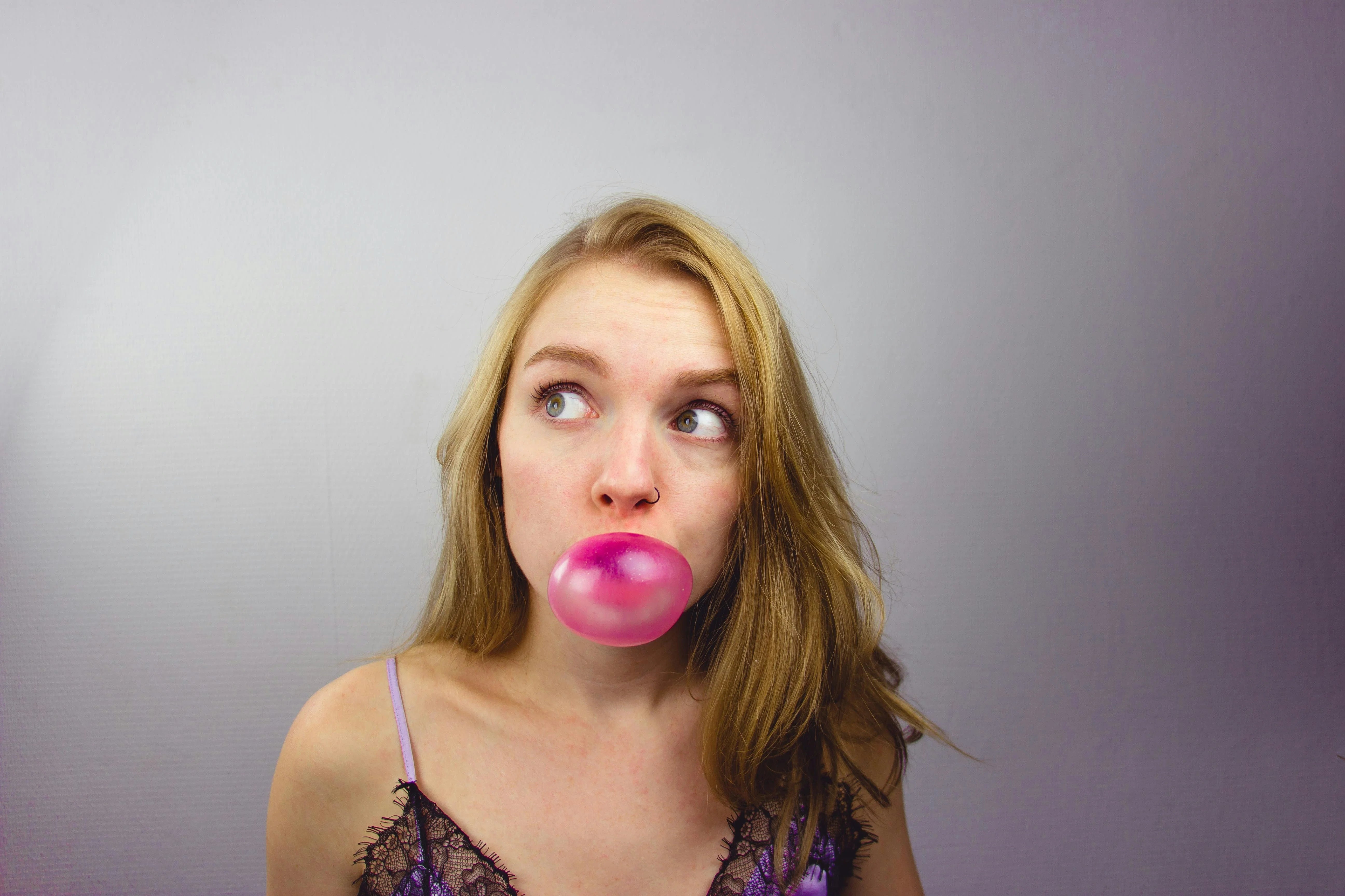 blond woman blowing a bubble with chewing gum